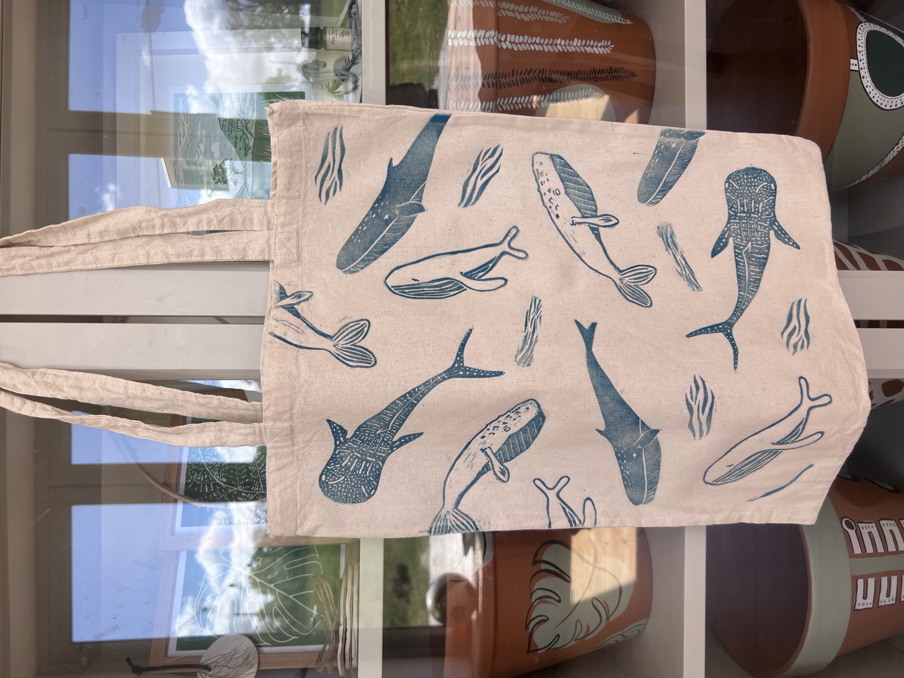 A handmade fabric tote decorated with blue whale and fish illustrations
